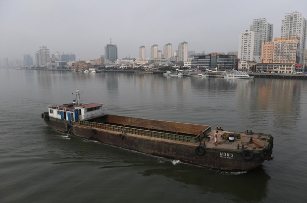 Coreia do Norte, Kim Jong-un, sanções, bloqueio naval - Um navio norte-coreano passa pela cidade fronteiriça chinesa de Dandong (no fundo), na província de Liaoning, no Norte de China, em 4 de setembro de 2017 (Greg Baker/AFP/Getty Images)