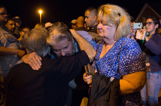 Ted e Ann Montgomery, funcionários da Primeira Igreja Batista, são consolados pelo governador texano Greg Abbott (à esquerda), após uma vigília de velas realizada na rua da igreja em 5 de novembro de 2017. (Suzanne Cordeiro/AFP/Getty Images)