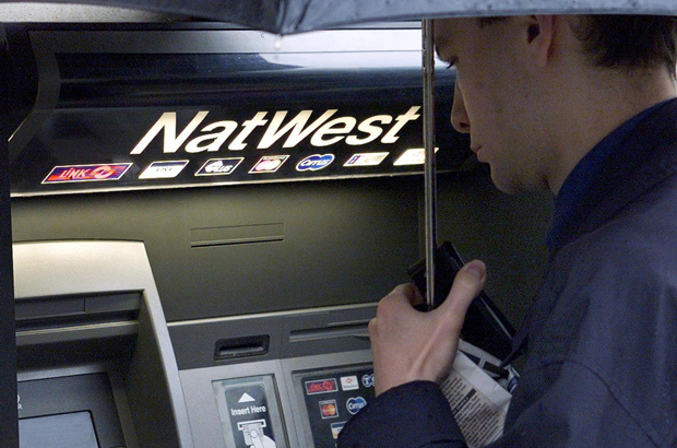 RBS, Natwest, demissões - Um homem usa um caixa eletrônico diante de uma agência do banco NatWest em The Strand, no centro de Londres (Jonathan Utz/AFP/Getty Images)