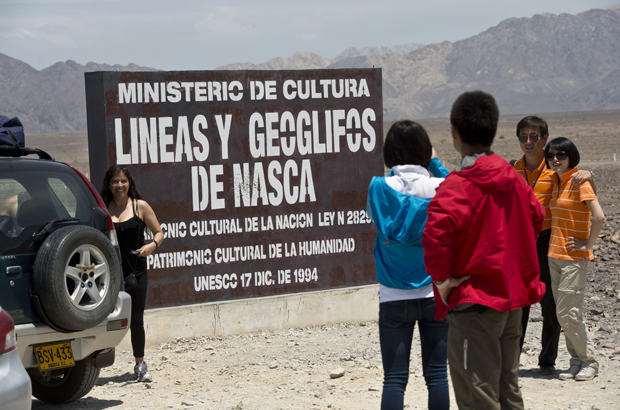 Linhas de Nazca, geoglifos - Turistas posam para fotos ao lado de um sinal em Nazca, 450 km ao sul de Lima, no Peru, em 12 de dezembro de 2014 (Martin Bernetti/AFP/Getty Images)