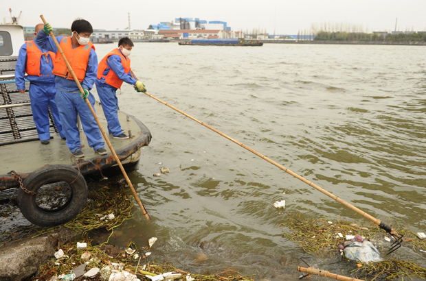 China, Taiwan, meio ambiente, repressão, autoritarismo - Funcionários sanitários coletam lixo não tratado despejado na principal via fluvial de Xangai em 11 de março de 2013 (Peter Parks/AFP/Getty Images)