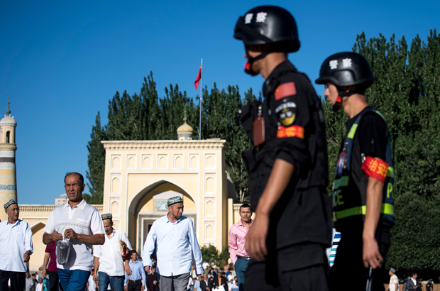 China, Xinjiang, uigures, repressão - Policiais patrulham as ruas enquanto uigures deixam a mesquita Id Kah na velha cidade de Kashgar, na província de Xinjiang, China, em 26 de junho de 2017 (Johannes Eisele/AFP/Getty Images)