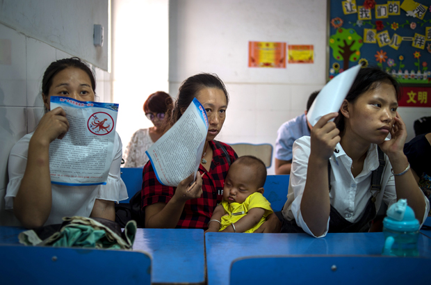 China, esquema Ponzi, esquema em pirâmide, fraude - Pessoas envolvidas num esquema de pirâmide esperam para serem questionadas pela polícia da cidade de Wuhan, na província de Hebei, no centro da China, em 23 de agosto de 2017 (STR/AFP/Getty Images)