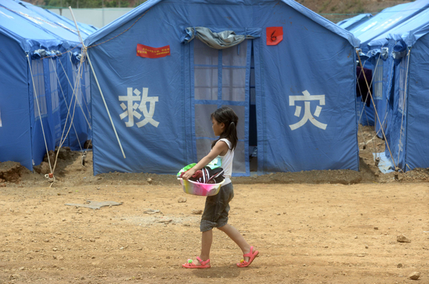 China, terremoto, corrupção, protesto, assistência social, Yunnan - Uma menina chinesa carrega uma bacia de roupas num abrigo temporário na cidade de Longtoushan, no condado de Ludian, após o terremoto de Yunnan, em 7 de agosto de 2014 (AFP/Getty Images)