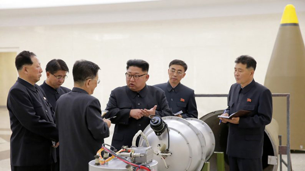 Coreia do Norte, Kim Jong-un, desertor, suicídio, programa nuclear - O líder Kim Jong-un (centro) conversa com autoridades norte-coreanas próximos do que seria o protótipo de uma ogiva nuclear num local não revelado, nesta foto publicada pela mídia estatal KCNA em 3 de setembro de 2017 (STR/AFP/Getty Images)